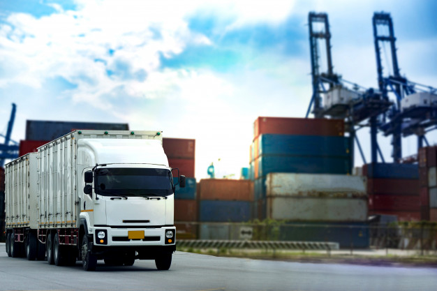 camion-contenedor-carga-blanca-puerto-barcos-logistica_42493-221